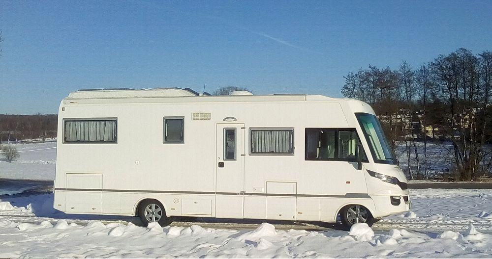 Weißes Reisemobil in winterlicher Landschaft