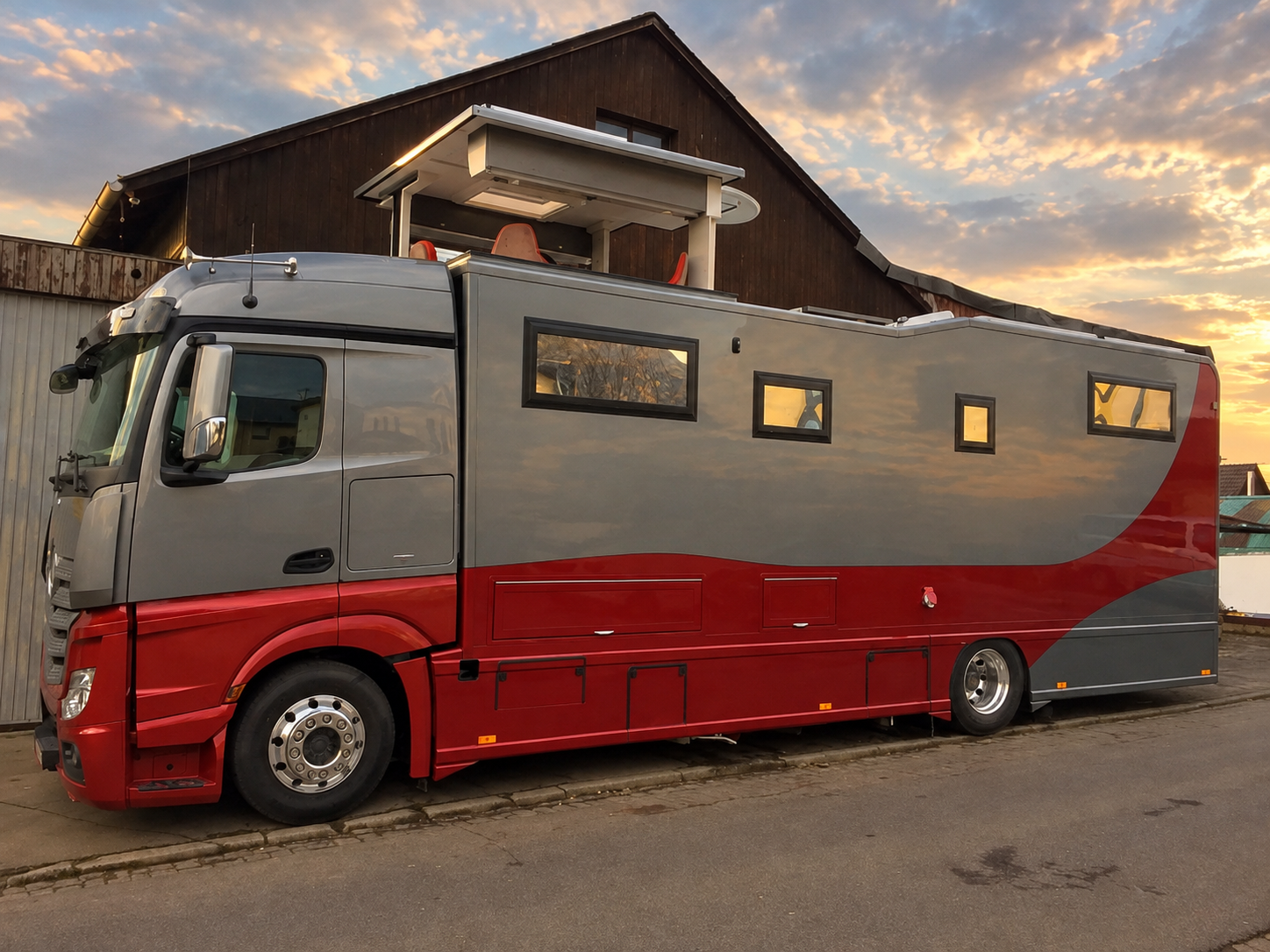 Individuell ausgebautes Reisemobil auf LKW-Basis in Grau und Rot mit ausfahrbarem Dachaufbau